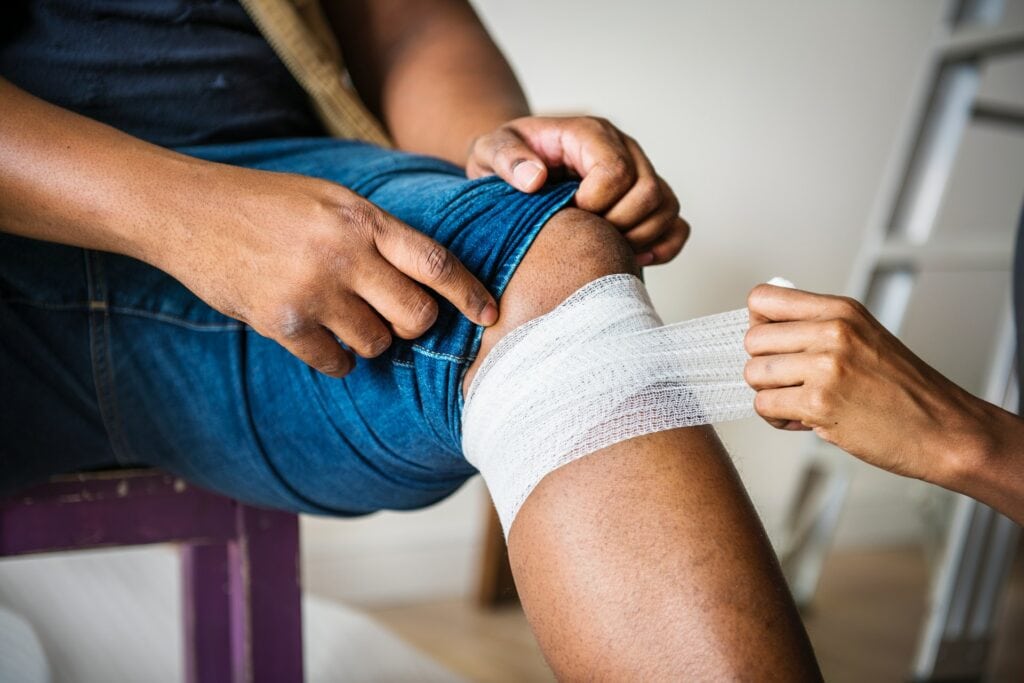 Einer Person wird ein Verband am Knie angelegt.