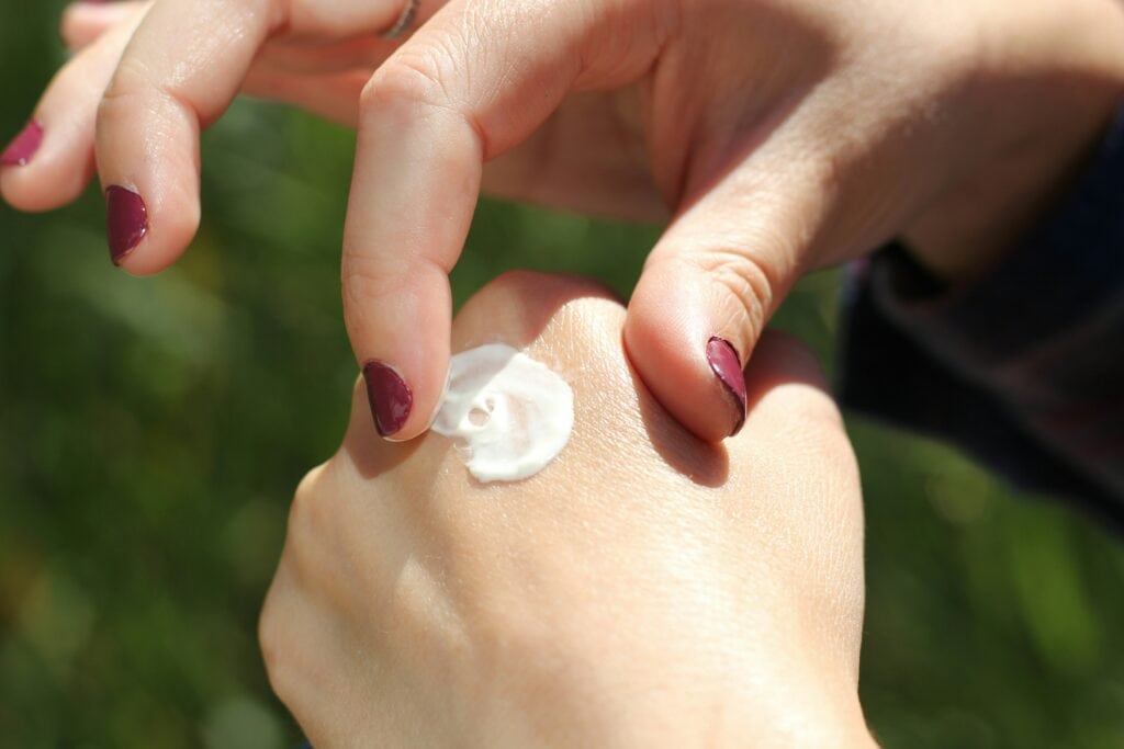 Gepflegte Hände auf die Handcreme aufgetragen wird.