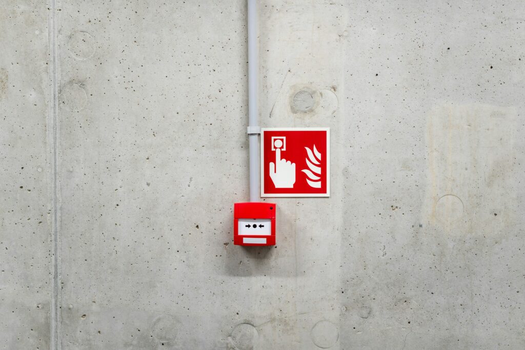 Ein Warnzeichen über einem manuellen Brandmelder.