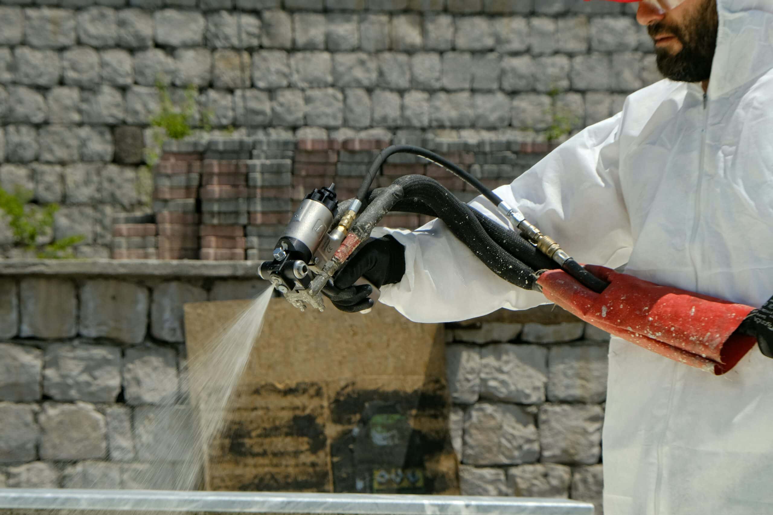 Eine Person in Schutzkleidung versprüht ein Biozidprodukt.