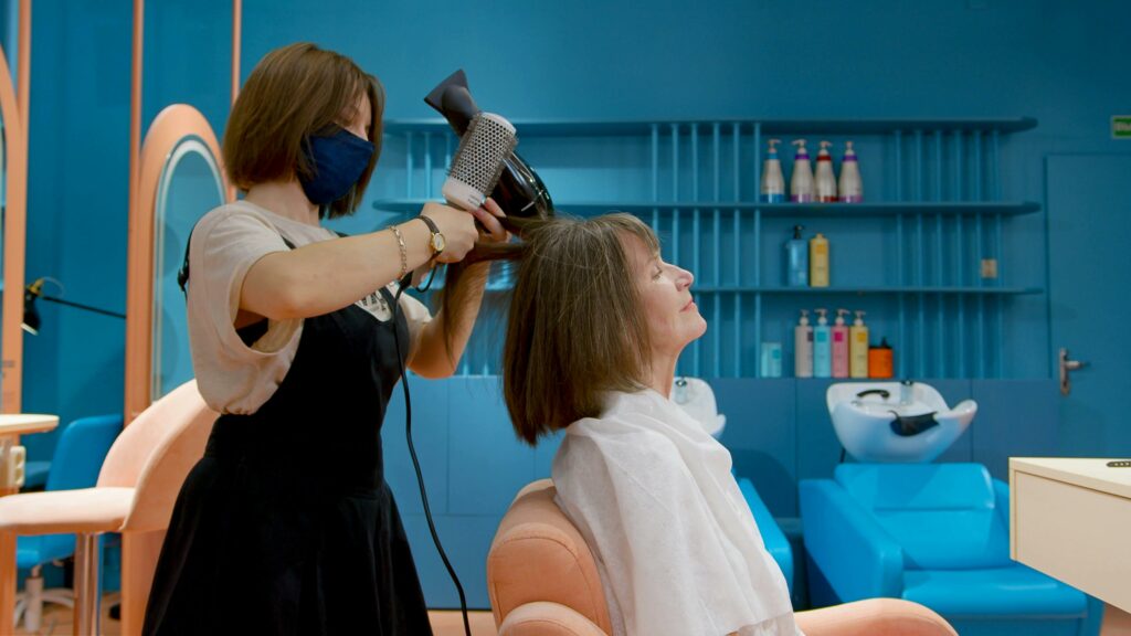 Eine Friseurin föhnt die Haare einer Kundin.