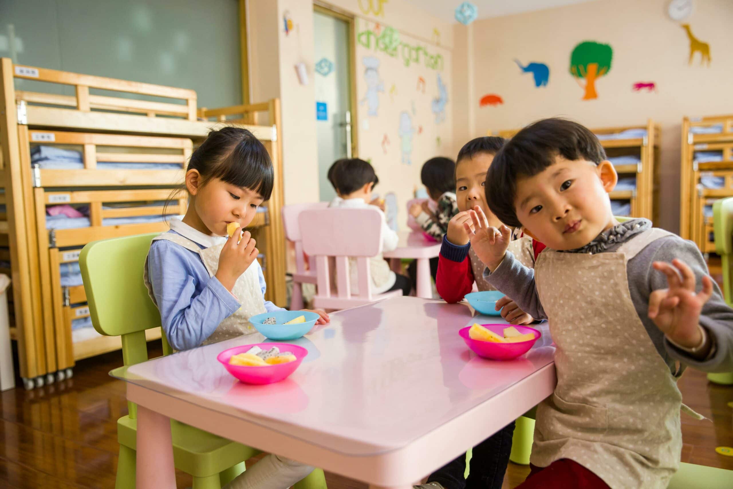 Kinder in einer Kita sitzen zusammen am Tisch und essen.