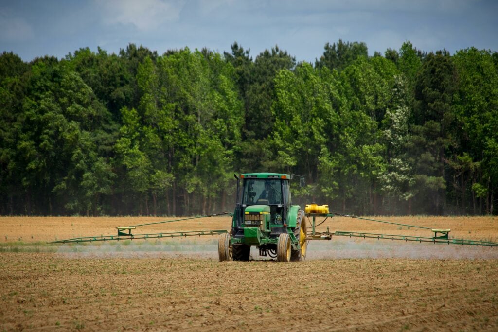 Ein Traktor verteilt Produkte zur Schädlingsbekämpfung auf einem Feld.