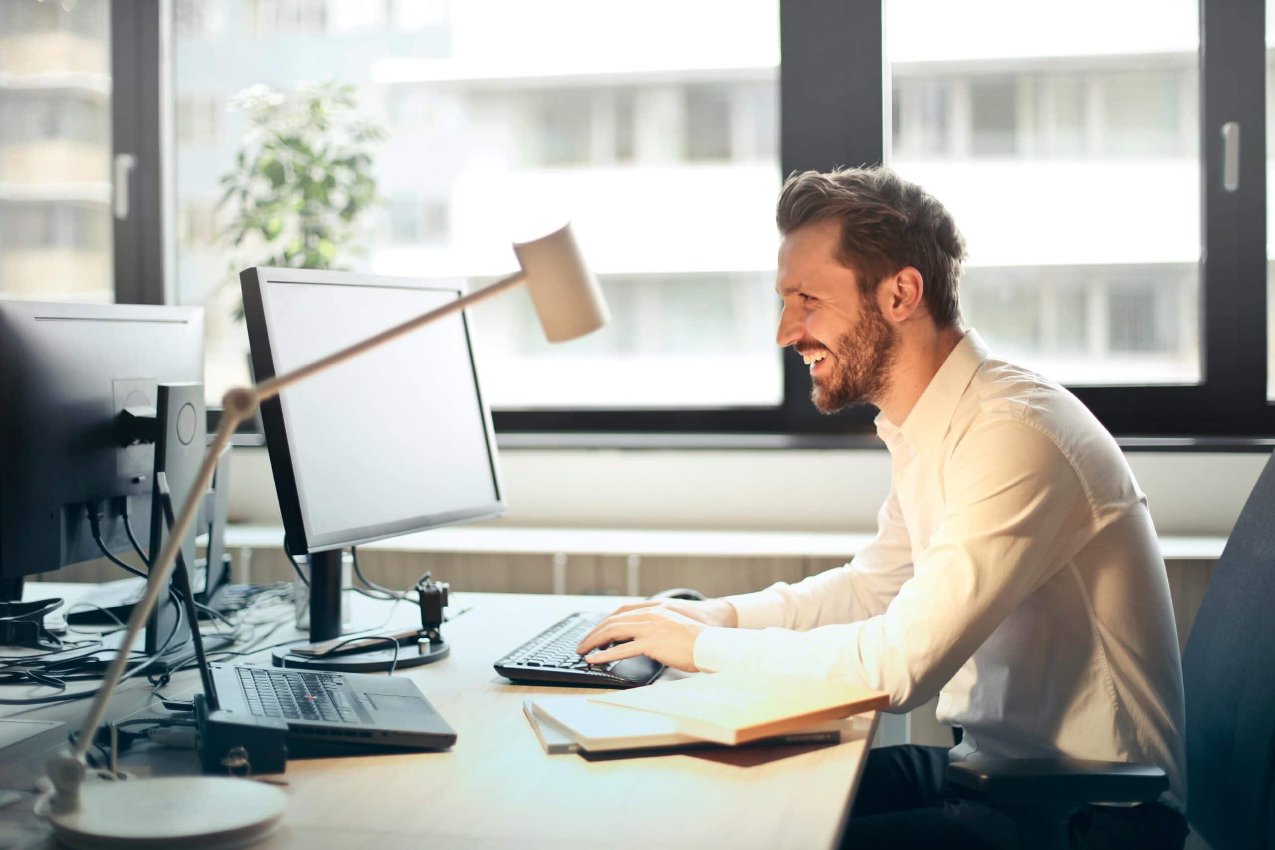 Person sitzt am Schreibtisch und arbeitet am PC