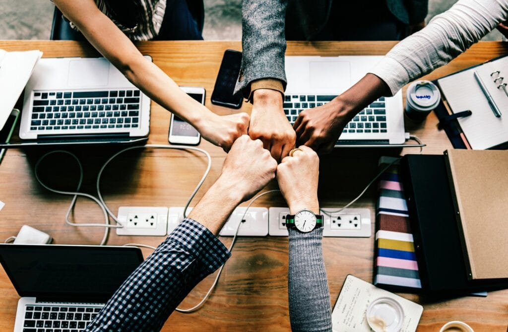 Arbeitnehmende sitzen an einem Tisch und arbeiten im Team