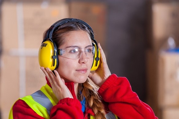 Eine Frau trägt einen Gehörschutz, um Lärmschwerhörigkeit vorzubeugen.