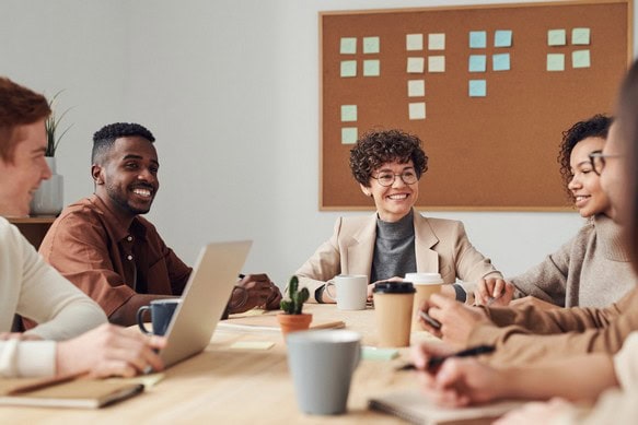 Arbeitgeberin lächelt ihren Angestellten während einer Konferenz freundlich zu
