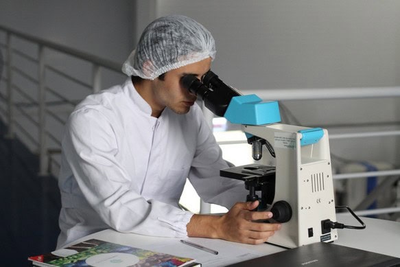Hygienemanager mikroskopiert etwas in Schutzkleidung