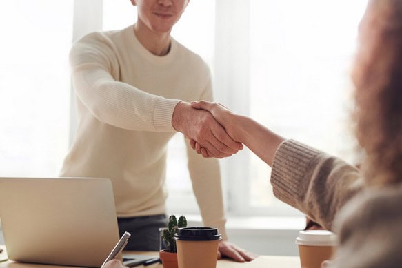 Arbeitnehmer und Arbeitgeberin geben sich die Hand